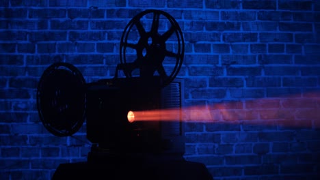 Silhouette-Eines-16-mm-Filmprojektors-Mit-Einem-Blau-Beleuchteten-Backsteinmauerhintergrund
