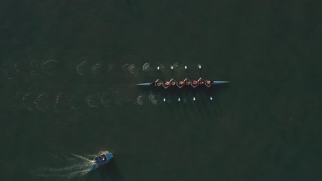 Top-aerial-directly-above-shot-of-rowing-crew-and-accompanying-boat