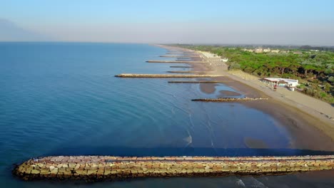 Birds-eye-view-of-calm-and-quiet-waters-of-Adriatic-sea-moving-towards-the-beach-of-coastal-town-Caorle,-Italy