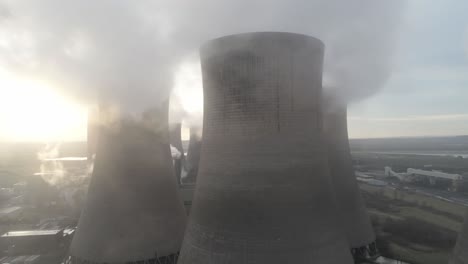 Aerial-orbit-pull-back-view-across-UK-power-station-cooling-towers-smoke-steam-emissions-at-sunrise