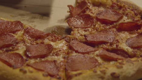 Slice-of-Pepperoni-Pizza-being-grabbed-from-whole-pizza---close-up