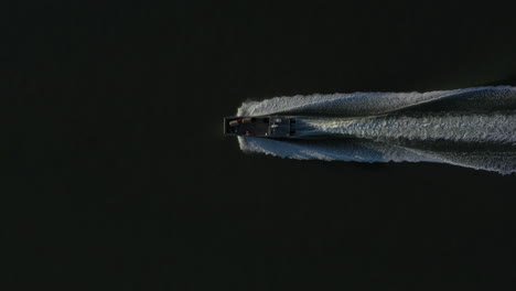 Aerial-directly-above-shot-of-motorboat-sailing-across-sea-at-maximum-speed