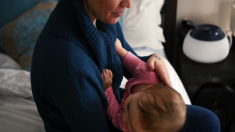 Mother-embracing-baby-girl-in-living-room