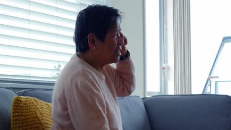 Senior-woman-talking-on-mobile-phone-in-living-room