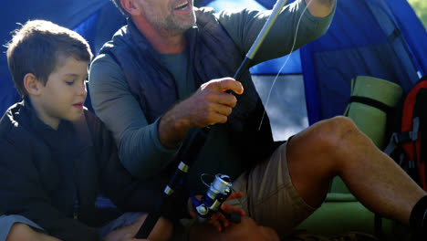 Father-and-son-holding-a-fishing-rod-outside-the-tent
