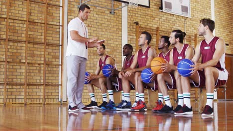 Basketball-coach-assisting-players-on-digital-tablet