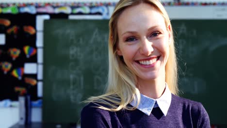 Portrait-of-happy-teacher-standing-in-classroom