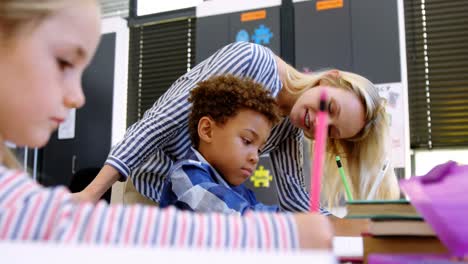 Teacher-helping-schoolboy-with-her-homework-in-classroom