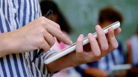 Teacher-standing-holding-digital-tablet