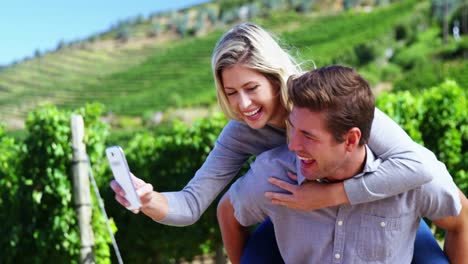 Happy-couple-taking-selfie-on-mobile-phone-in-vineyard
