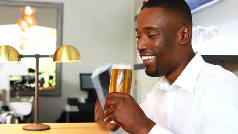 Man-talking-on-mobile-phone-while-having-beer-at-counter