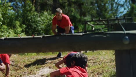 Niños-Arrastrándose-Bajo-La-Red-Durante-El-Entrenamiento-De-Carrera-De-Obstáculos