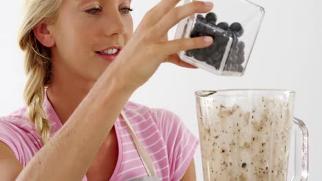 Woman-preparing-smoothie-against-white-background