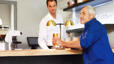Mature-man-interacting-with-waiter-while-drinking-beer