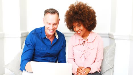 Smiling-couple-discussing-over-laptop
