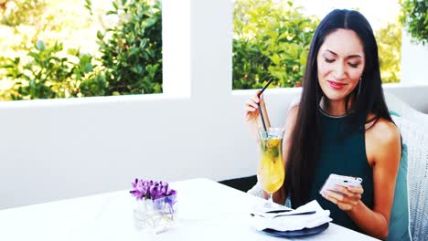 Beautiful-woman-using-mobile-phone-while-drinking-mocktail