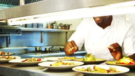 Chef-garnishing-meal-at-order-station-of-commercial-kitchen