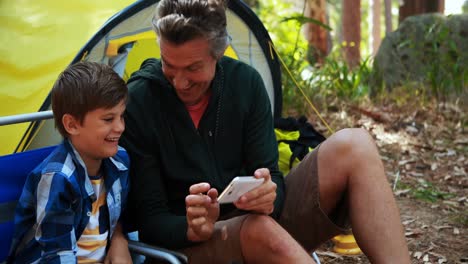 Father-and-son-taking-a-selfie-on-mobile-phone-outside-tent