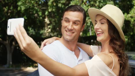 Couple-taking-a-selfie-on-mobile-phone-near-car