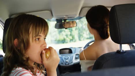 Mädchen-Mit-Apfel-Auf-Dem-Rücksitz-Des-Autos