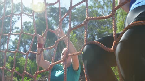 Determined-women-climbing-a-net-during-obstacle-course