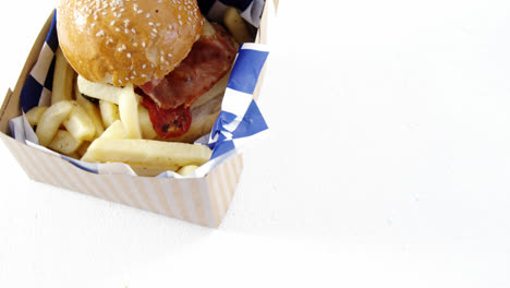 Hamburger-and-french-fries-in-a-take-away-container-on-table