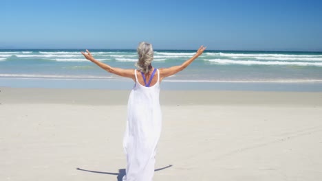 Blissful-senior-woman-walking-at-beach