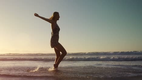 Woman-with-arms-outstretched-playing-in-water-at-beach