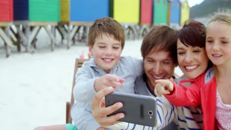 Glückliche-Familie,-Die-Am-Strand-Ihr-Mobiltelefon-Benutzt