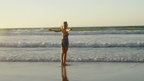 Woman-with-arms-outstretched-playing-in-water-at-beach