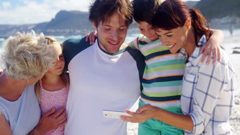 Multi-generation-family-using-mobile-phone-at-beach