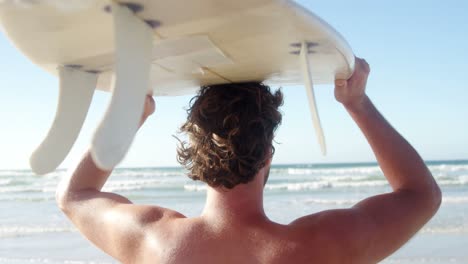 Hombre-Llevando-Tabla-De-Surf-En-La-Cabeza-En-La-Playa-En-Un-Día-Soleado