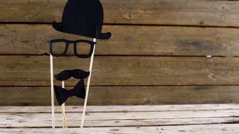 Bow-tie,-spectacles-and-fake-mustache-arranged-on-wooden-plank