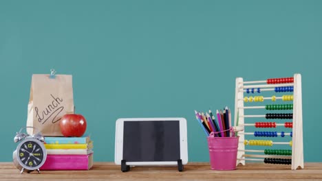 School-accessories-with-digital-tablet,-lunch-and-alarm-clock-on-table