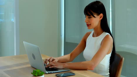 Female-executive-using-laptop-and-mobile-phone
