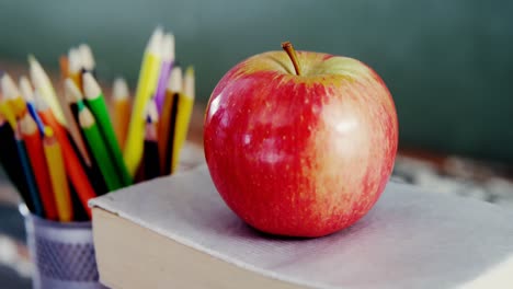 Apfel-Auf-Buch-Mit-Farbstift-Auf-Tisch