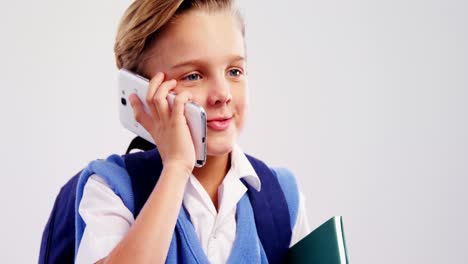 Schuljunge-Spricht-Mit-Dem-Handy-Vor-Weißem-Hintergrund