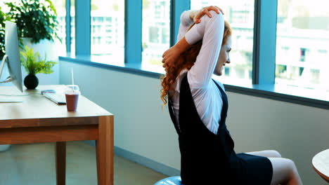 Female-executive-doing-stretching-exercise-while-working-at-her-desk