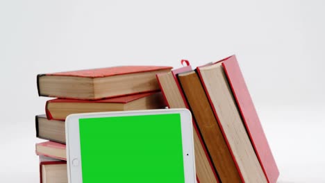 Stack-of-books-with-digital-tablet-against-white-background