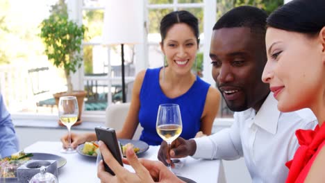 Friends-using-mobile-phone-while-having-meal