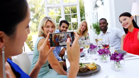 Woman-photographing-of-friends-sitting-at-table