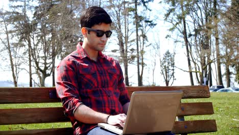 Man-using-laptop-in-the-park-4k