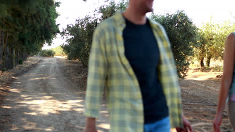Couple-walking-with-a-basket-of-olives-in-farm