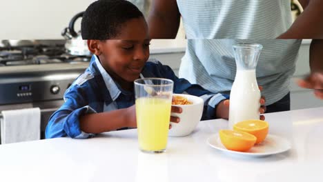 Father-pouring-milk-into-sons-cereal-in-kitchen