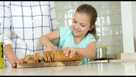 Mother-assisting-daughter-in-cutting-bread-loaf
