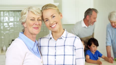 Smiling-senior-woman-and-daughter-standing-with-arm-around-at-home