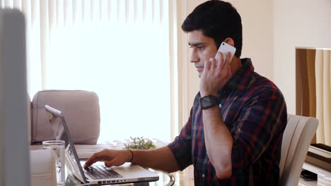 Man-talking-on-mobile-phone-while-using-laptop-4k