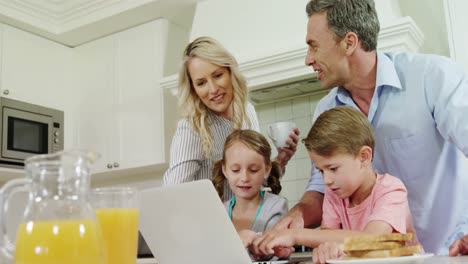 Familia-Usando-Una-Computadora-Portátil-Juntos-En-La-Cocina