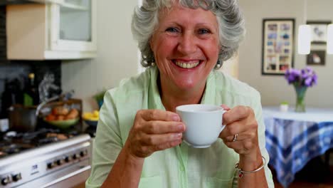 Happy-senior-woman-drinking-coffee-in-kitchen-4k