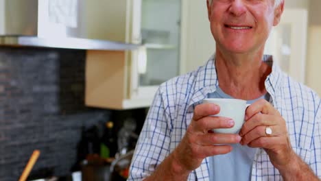 Happy-senior-man-having-coffee-in-kitchen-4k